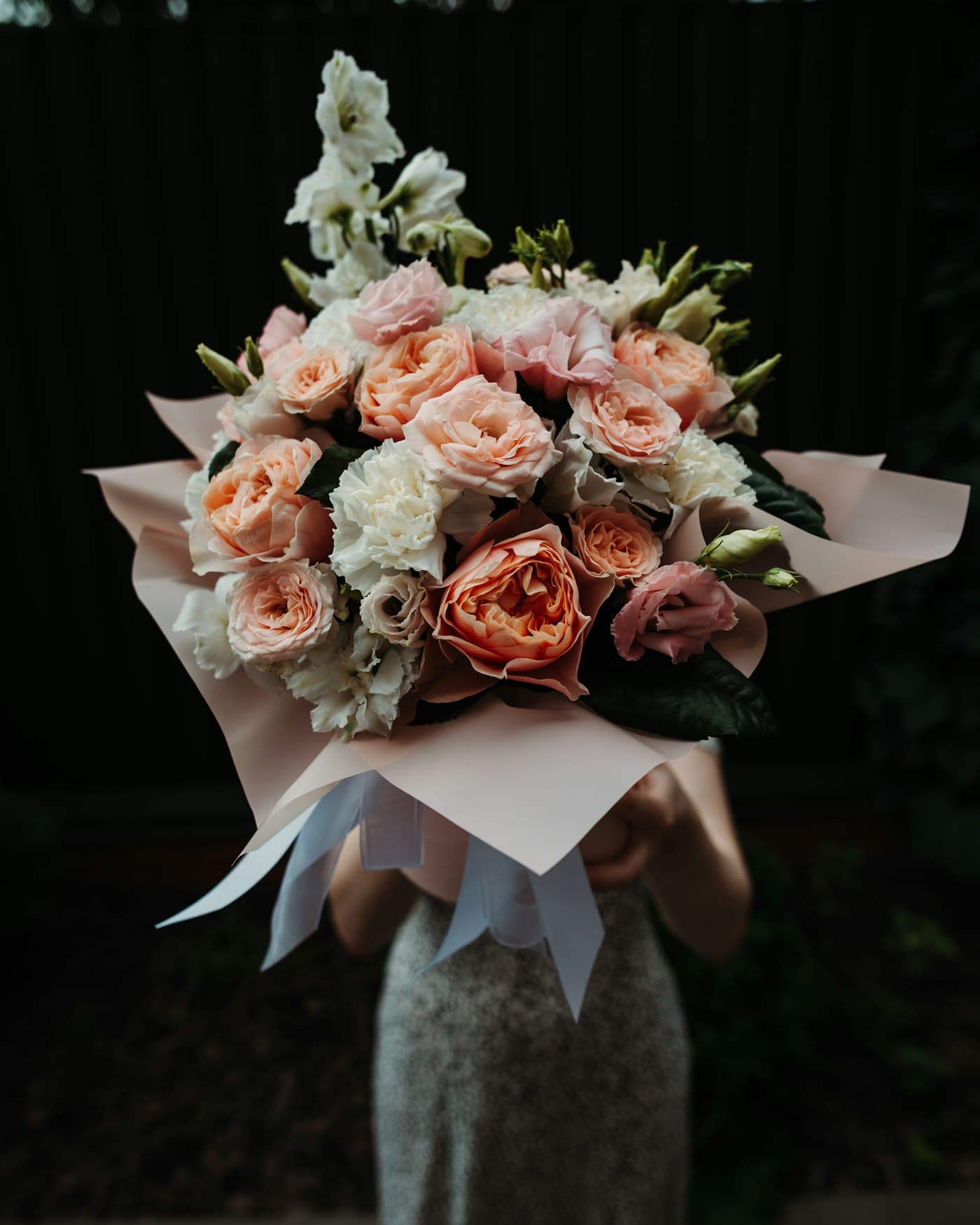 Bouquet de roses pêche et roses enveloppé de papier blanc